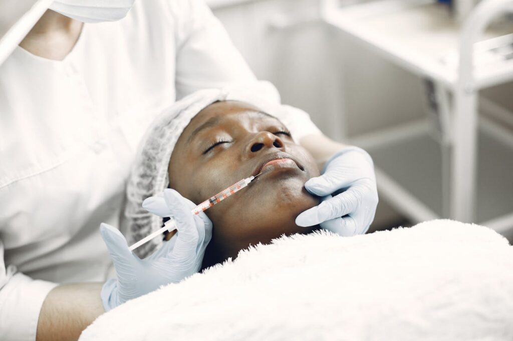 Un médecin réalisant l’injection d’agents de comblement sur le visage d’une femme